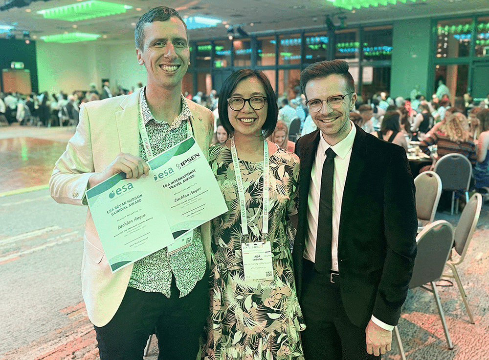 Three people standing together, all smiling and dressed professionally